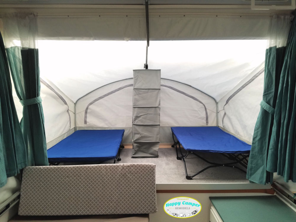 pop up camper bed with two cots and a hanging organizer divider